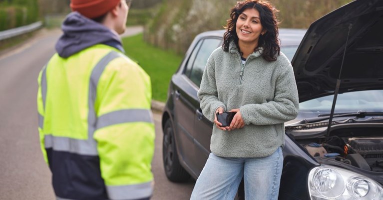 A woman talks to a breakdown recovery driver on a roadside