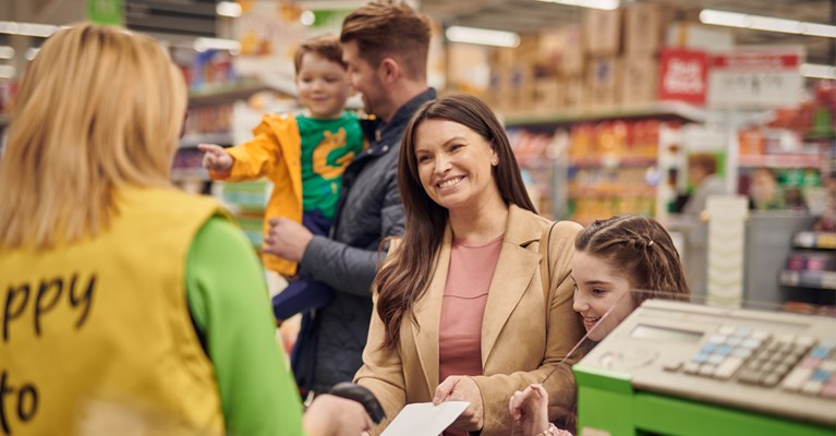 Family shopping and paying with a voucher at the checkout in Asda
