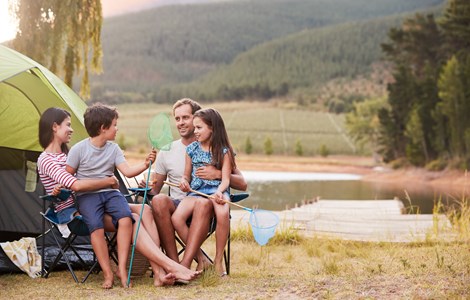 Young family camping by lake with fishing nets