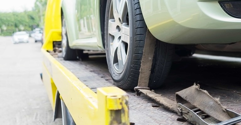 Broken down car on the back of a tow truck after calling breakdown cover provider