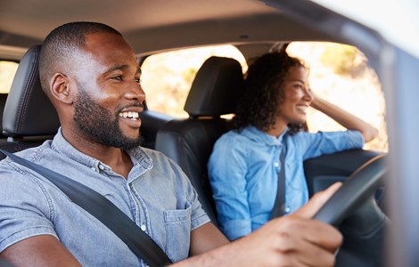 Young couple smiling and driving in car in blue shirts