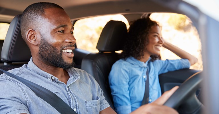 Young couple smiling and driving in car in blue shirts