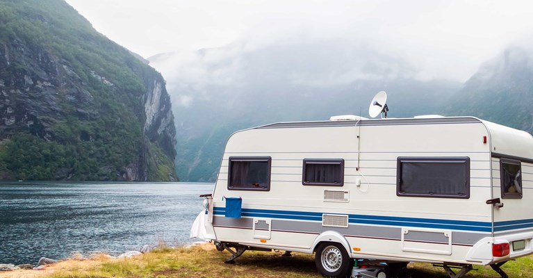 Caravan parked next to a lake and mountains