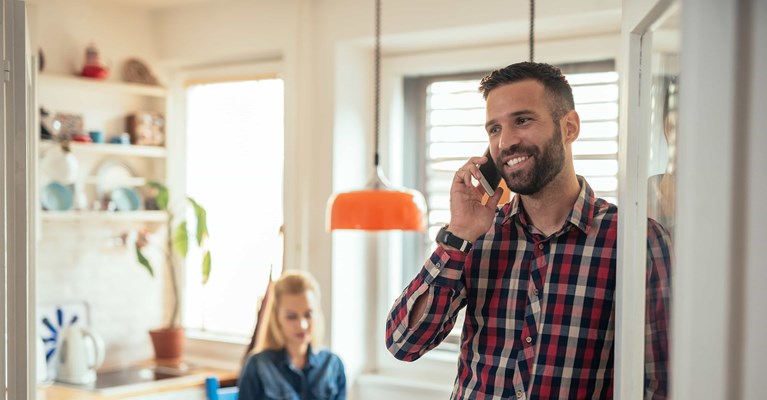 Young couple at home on laptop and phone looking into financial services