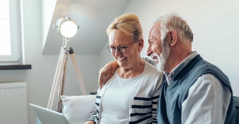 Older couple at home reviewing financial services on a laptop