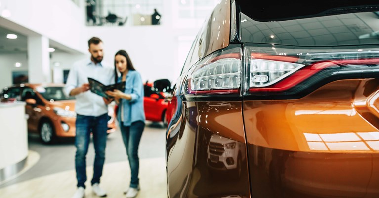 Young couple looking at a brochure buying a new car