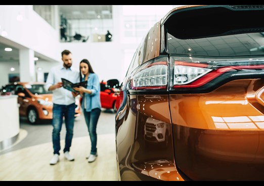 Young couple looking at a brochure buying a new car
