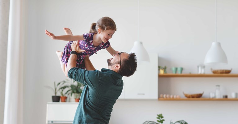 Man with glasses holding happy young girl in the air