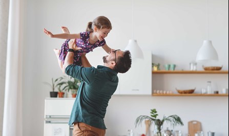 Man with glasses holding happy young girl in the air