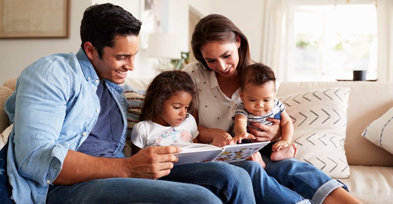 Young family reading a book together in their home