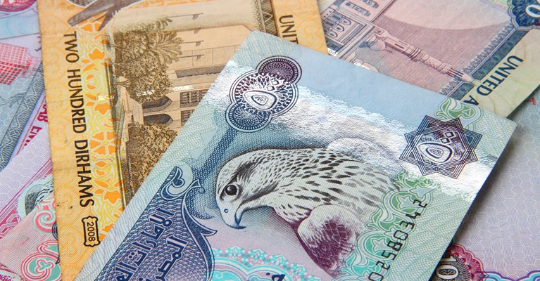 Pile of mixed denomination UAE dirham banknotes available at travel money bureaux