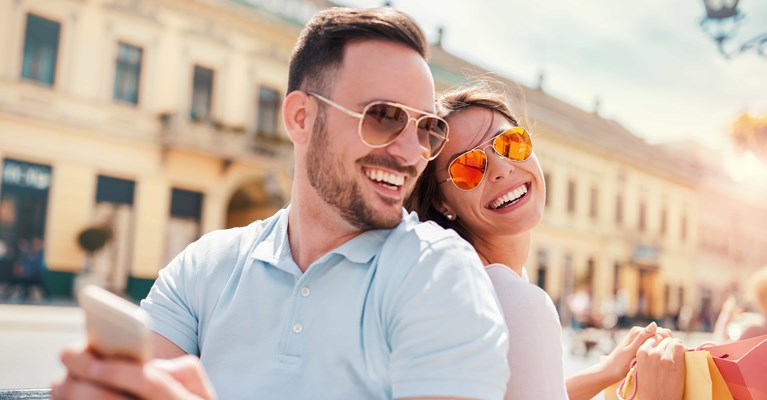 Happy couple on mobile phone relaxing after shopping