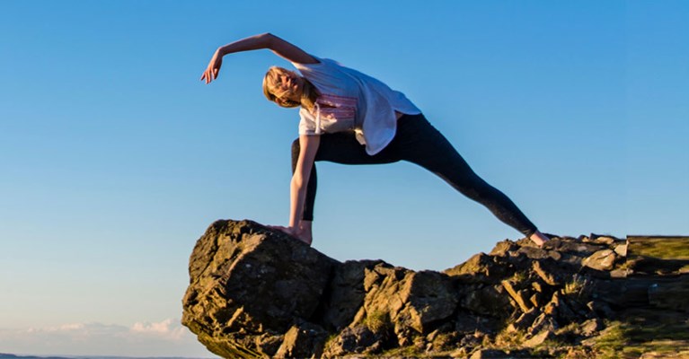 a woman doing yoga on a cliff