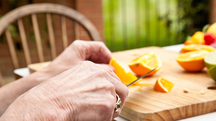 old hands chopping oranges