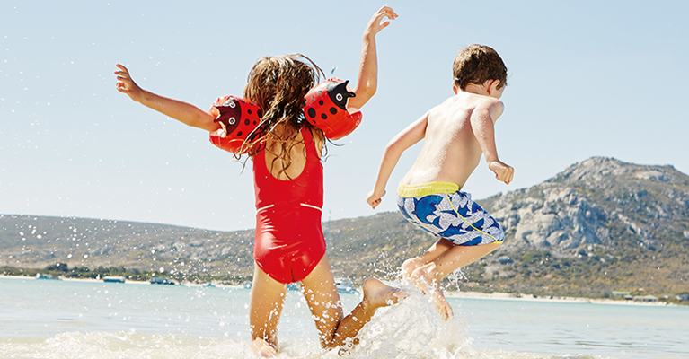 a boy and girl playing in the water on a beach