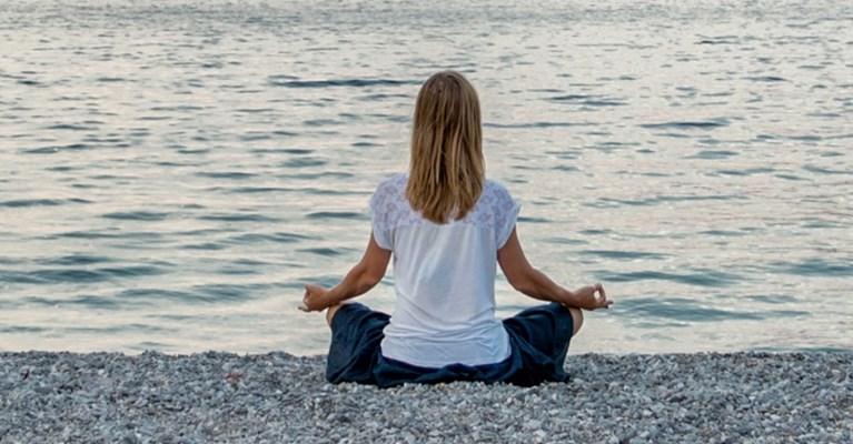 Woman doing yoga on a pebble beach