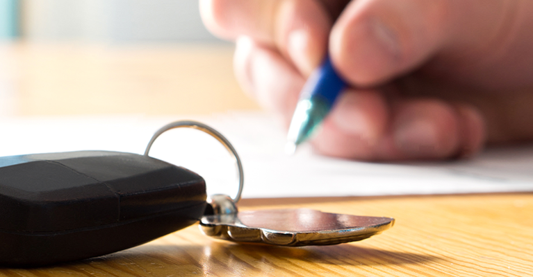 Car key on a table as hands fill in a form