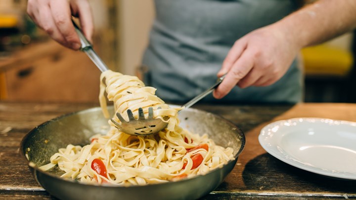 man serving up tagliatelle