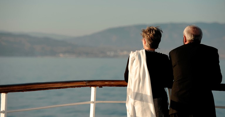 Older couple standing at the rail of a cruise ship