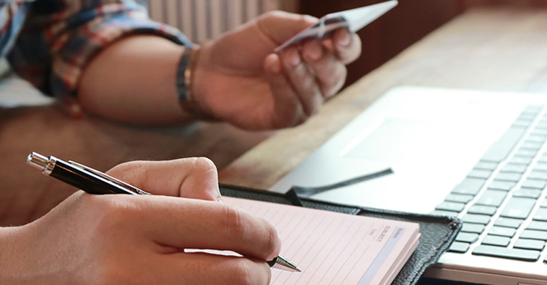 A man using a laptop, notepad and credit card