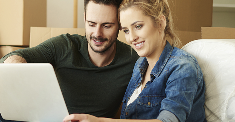 Couple using a laptop with a guitar in background