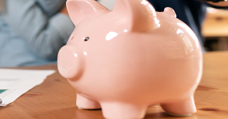 Piggy bank, calculator and paperwork on a table