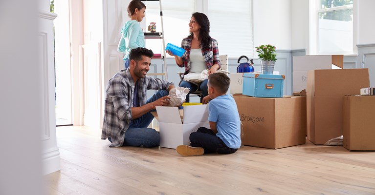 Young family of four unpacking their belongings whilst sat in their new house 