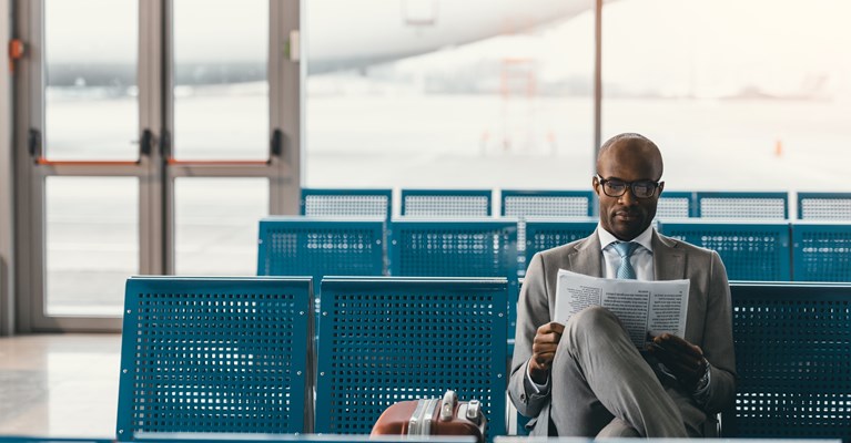 Man sat reading the paper in an empty airport lounge waiting for his flight