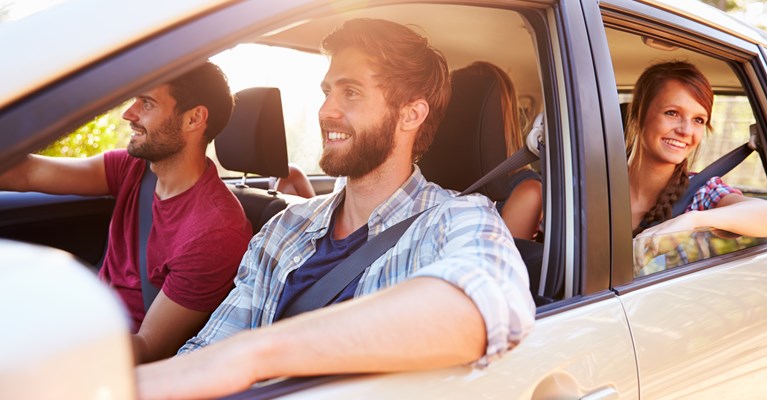 Four young friends sat in a silver car looking out of the car window