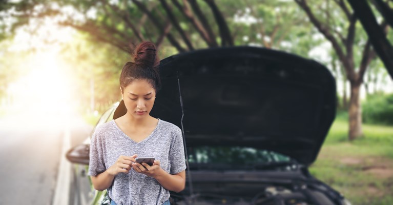 Young woman by the side of the road on phone with bonnet up