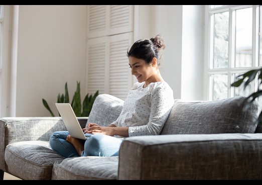 Lady sat on laptop on sofa