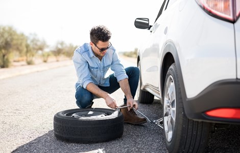 Man changing a tyre by the side of the road