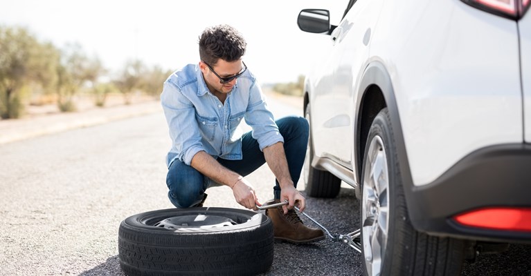 Man changing a tyre by the side of the road