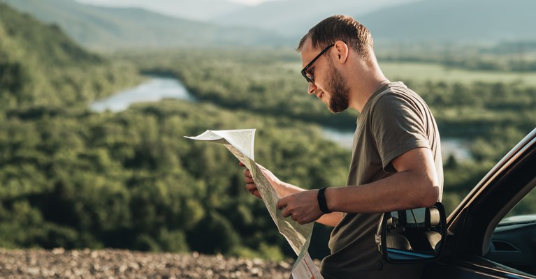 Man parked up outside car in county side looking at map