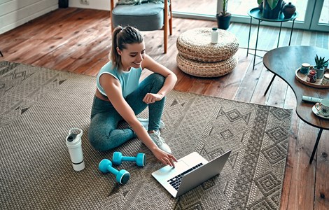 Lady doing workout on floor at home on laptop