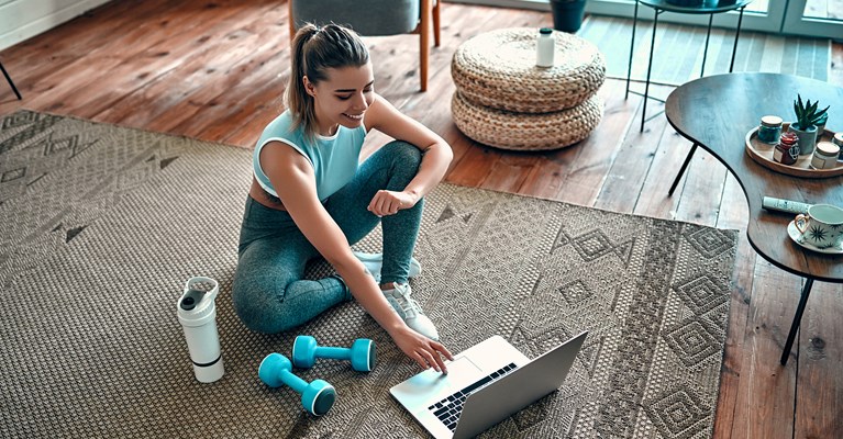 Lady doing workout on floor at home on laptop