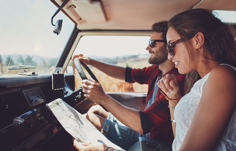 Couple in car driving and looking at a map