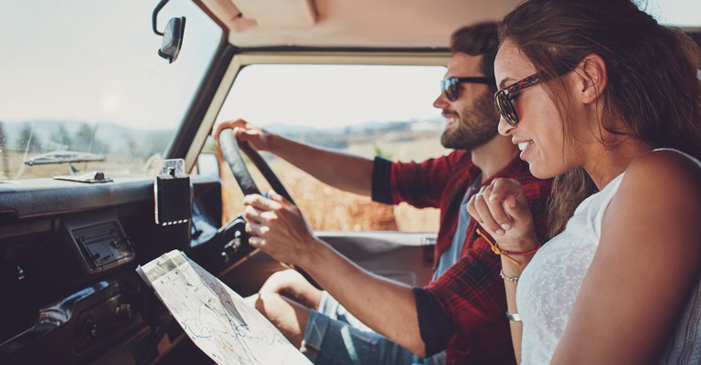 Couple in car driving and looking at a map