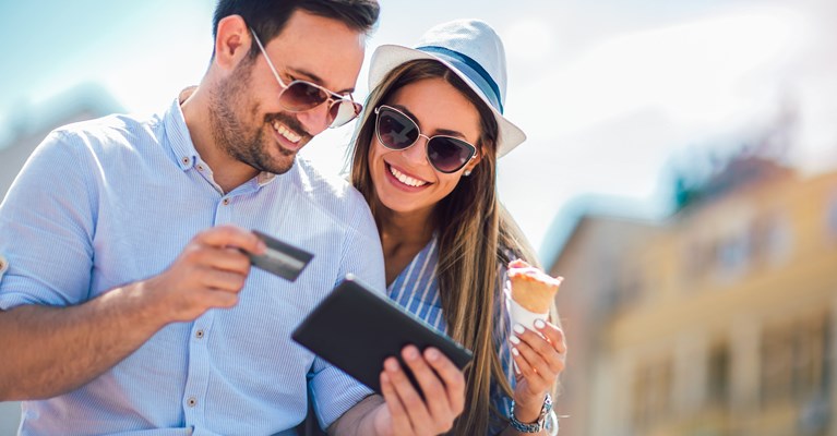 Couple sat with card and tablet in the sun eating ice cream