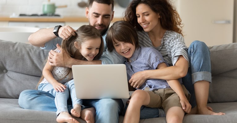 Parents and two children sat on sofa looking at laptop