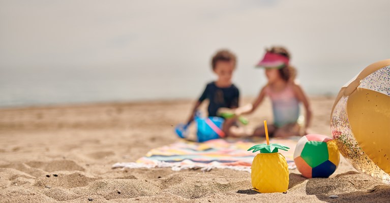 Young children on the beach playing with toys, beach balls in focus