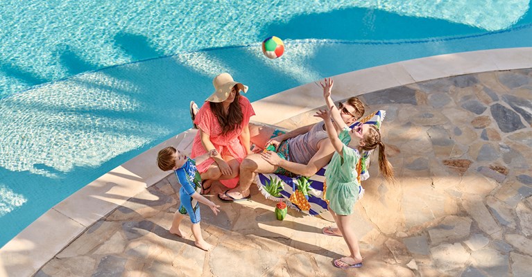 Family sat around a pool playing with a ball