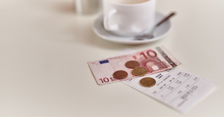 Euro notes and coins on table with receipt and coffee
