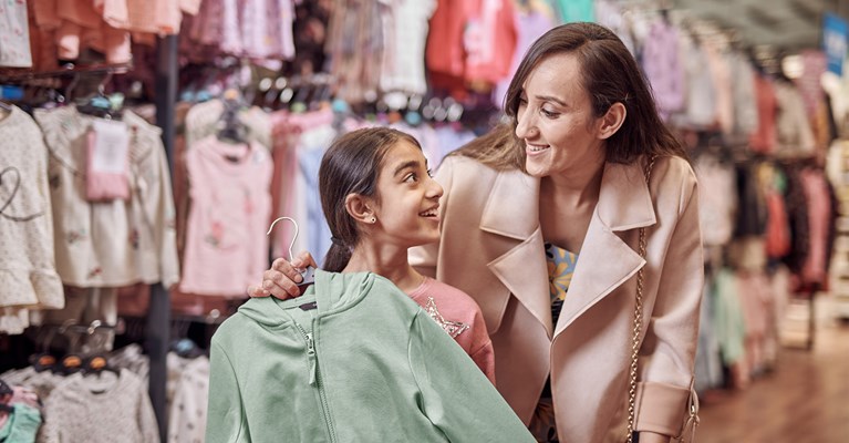 Mum and daughter clothes shopping in George looking at a green hoody