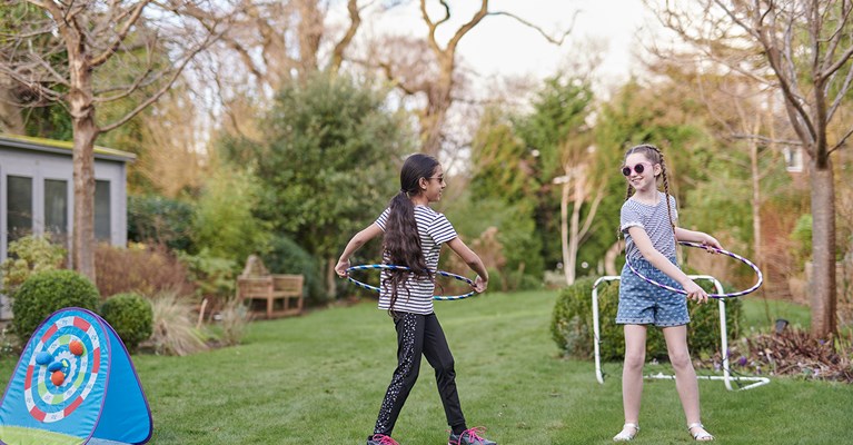 Two young girls playing with hula hoops in the garden