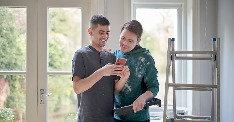 Male couple decorating house and looking at phone together