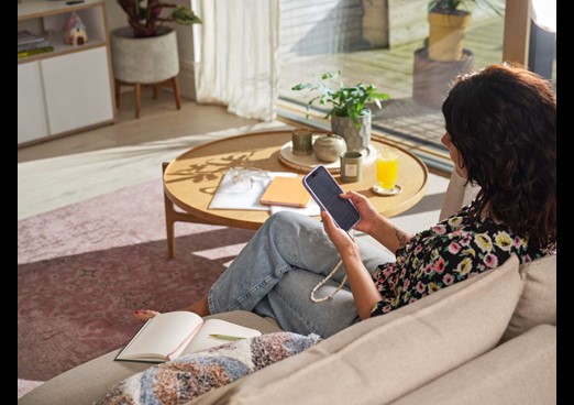 A young woman sits on a sofa looking at her phone