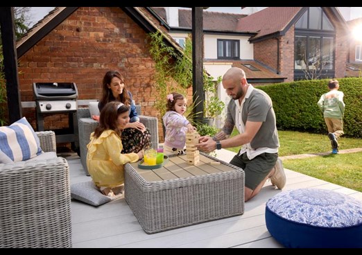 A family sit on the decking in their garden and play board games