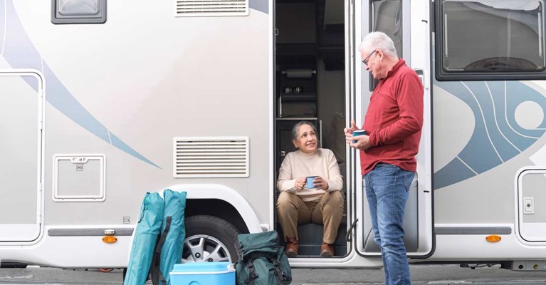A man and a woman talk outside of a motorhome
