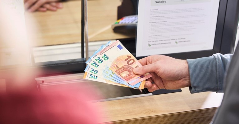 A man holds some euros at a travel money kiosk